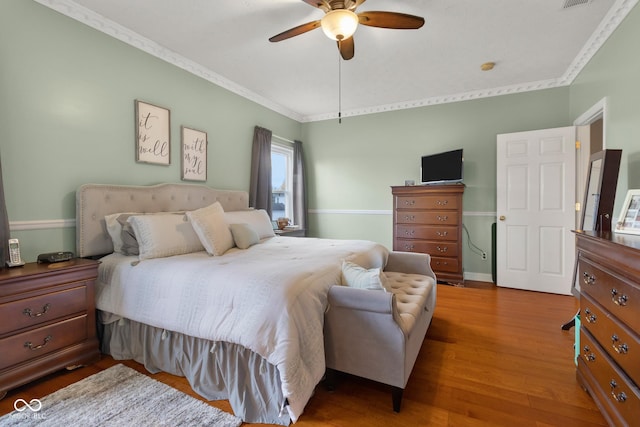 bedroom with ornamental molding, wood finished floors, and a ceiling fan