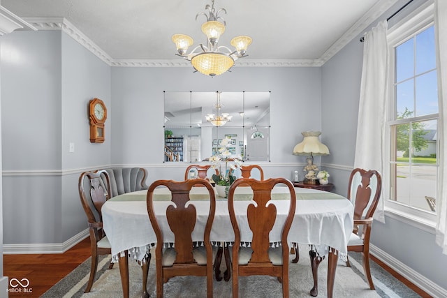 dining space featuring a chandelier, wood finished floors, baseboards, and crown molding