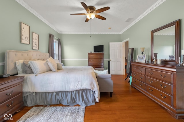 bedroom with crown molding, wood finished floors, and a ceiling fan