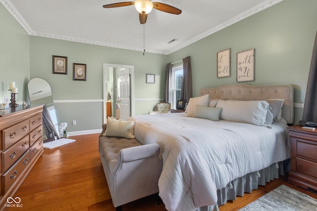 bedroom featuring ornamental molding, wood finished floors, baseboards, ceiling fan, and connected bathroom