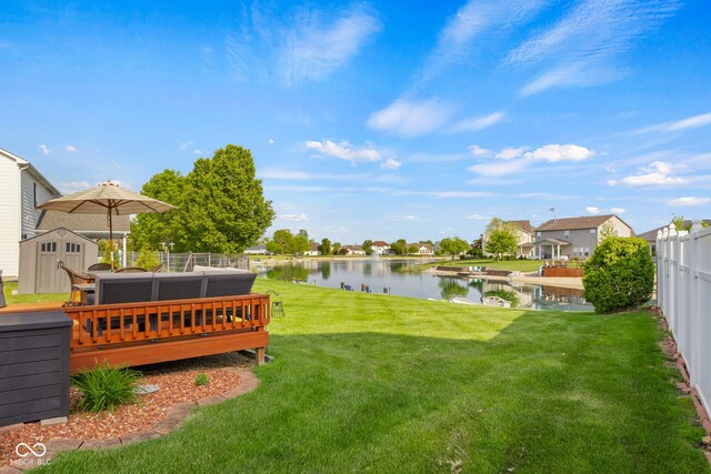 view of yard featuring a storage shed, a deck with water view, and an outdoor structure
