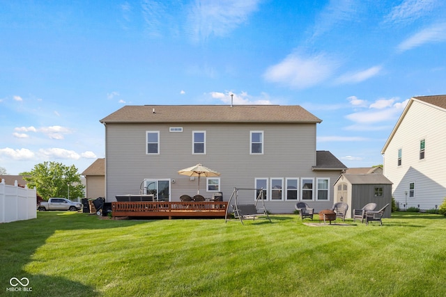 rear view of property featuring a storage unit, a fire pit, a deck, and a lawn