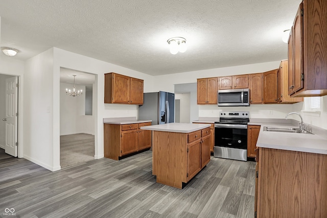 7156 Chemistry Ct, Indianapolis, IN 46239 - kitchen with stainless steel appliances, a sink, light wood-style floors, brown cabinetry, and a center island