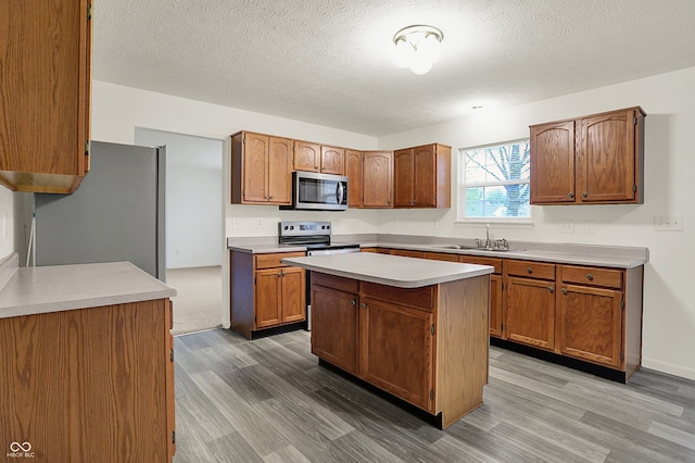 7156 Chemistry Ct, Indianapolis, IN 46239 - kitchen featuring stainless steel appliances, light wood-type flooring, a sink, light countertops, and a textured ceiling