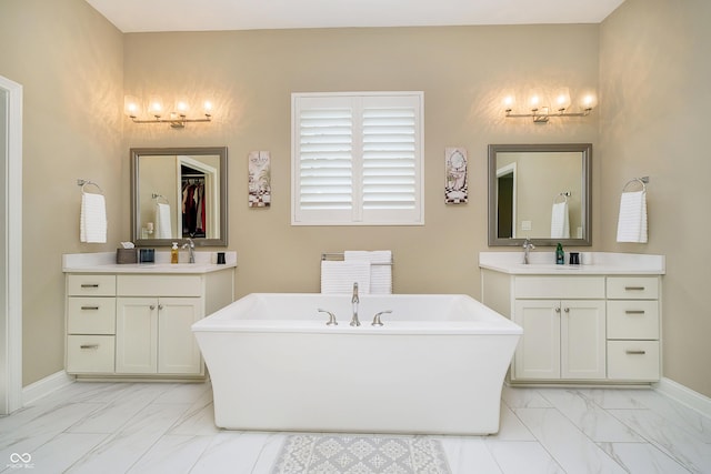 14003 Grannan Ln, Carmel, IN 46074 - full bath featuring marble look tile flooring, a freestanding bath, baseboards, and two vanities