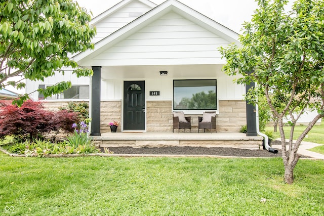 648 Market St, Hope, IN 47246 - view of front of house with a porch, a front lawn, stone siding, and board and batten siding
