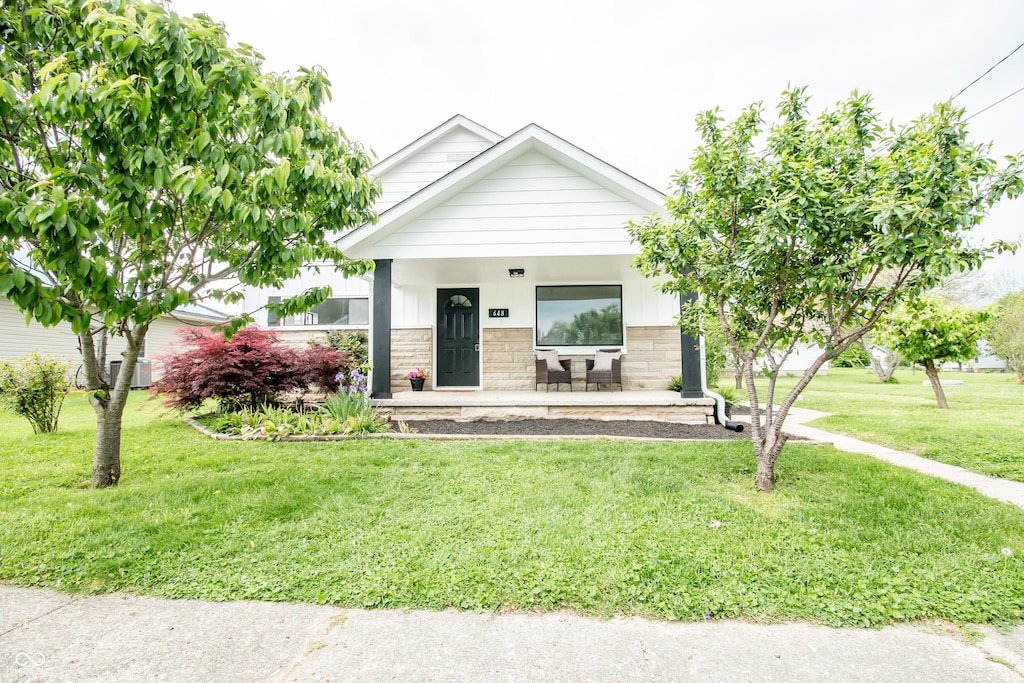 648 Market St, Hope, IN 47246 - view of front of home with stone siding, a front lawn, and covered porch