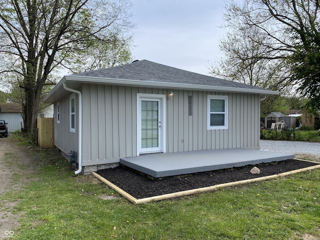 back of house with a shingled roof, board and batten siding, and a yard