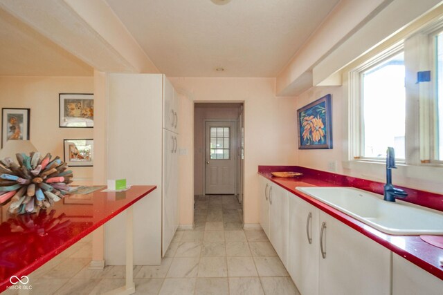 kitchen featuring a sink, white cabinets, and baseboards