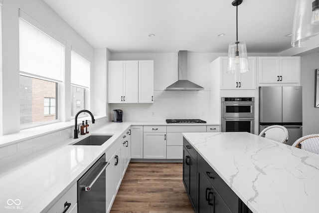127 Monon Green Blvd, Carmel, IN 46032 - kitchen featuring appliances with stainless steel finishes, wall chimney exhaust hood, white cabinetry, hanging light fixtures, and recessed lighting