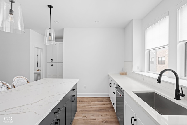 127 Monon Green Blvd, Carmel, IN 46032 - kitchen featuring dishwasher, light wood-style floors, white cabinets, hanging light fixtures, and light stone countertops