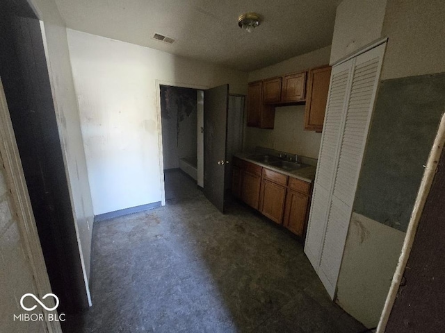 kitchen featuring brown cabinets, a sink, and concrete floors