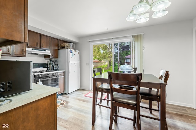 5120 Apache Ct, Columbus, IN 47203 - kitchen featuring freestanding refrigerator, range with gas cooktop, under cabinet range hood, light countertops, and a chandelier
