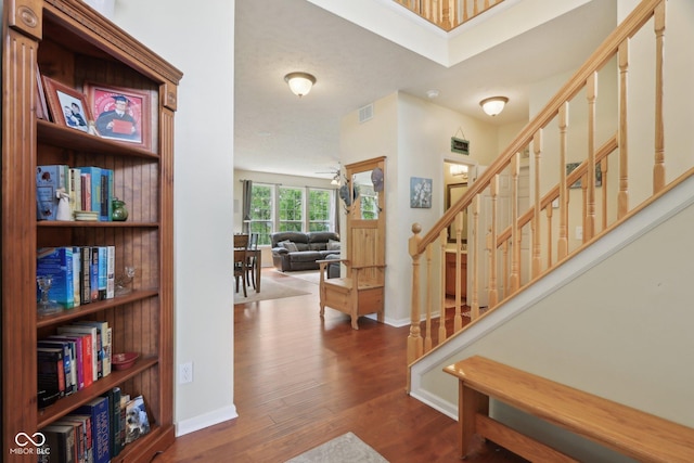 entryway with stairs, wood finished floors, and baseboards