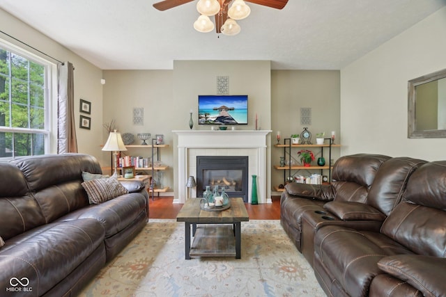 living area featuring ceiling fan, wood finished floors, and a fireplace