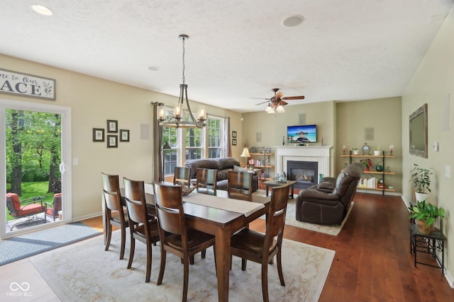 dining area featuring wood finished floors, a glass covered fireplace, ceiling fan, a textured ceiling, and recessed lighting