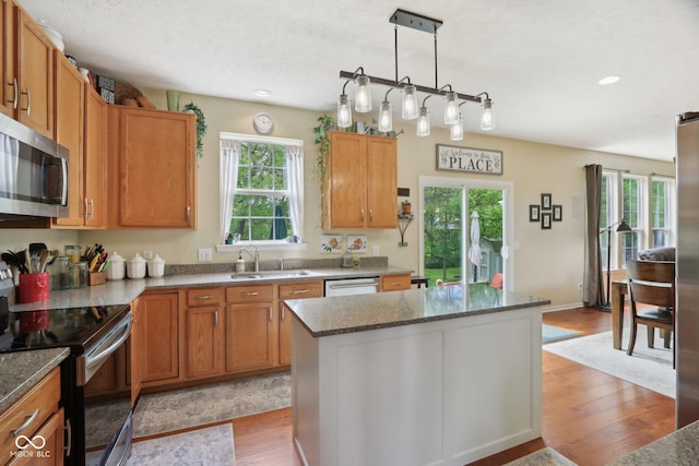 kitchen with appliances with stainless steel finishes, a sink, light wood-style floors, a center island, and recessed lighting