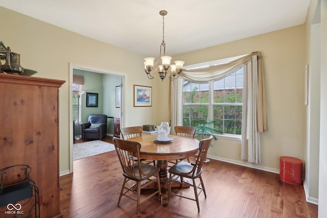 dining area with dark wood-style flooring, a chandelier, and baseboards