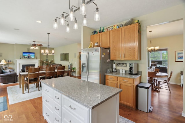 kitchen featuring stainless steel refrigerator with ice dispenser, a chandelier, ceiling fan, wood finished floors, and open floor plan