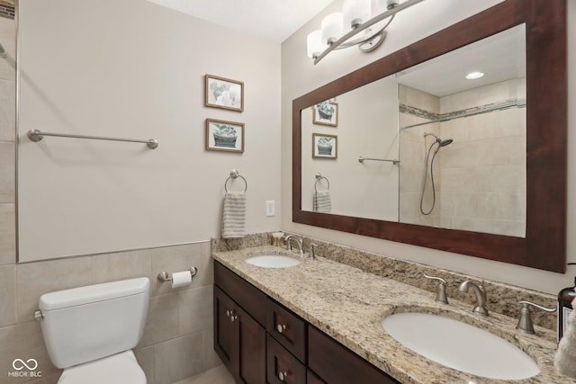 full bathroom with toilet, double vanity, and a tile shower