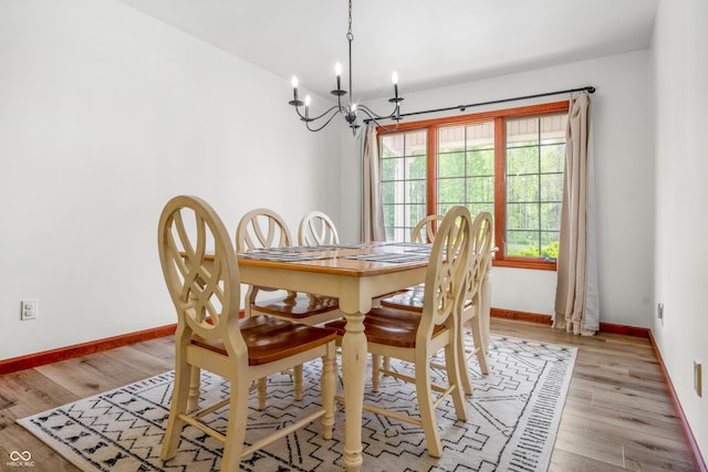 dining space with a chandelier, baseboards, and light wood-type flooring