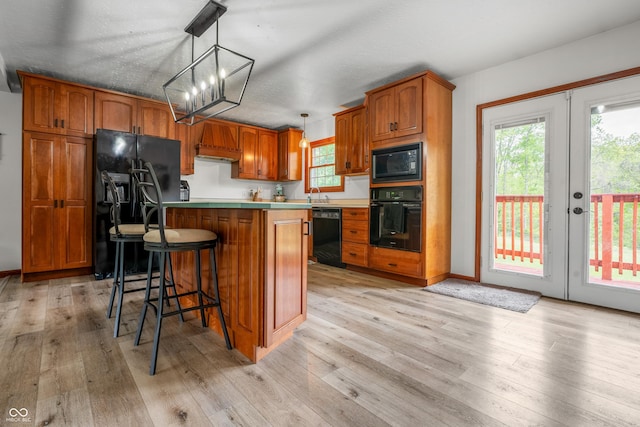 kitchen with black appliances, brown cabinets, light wood-style floors, french doors, and a chandelier