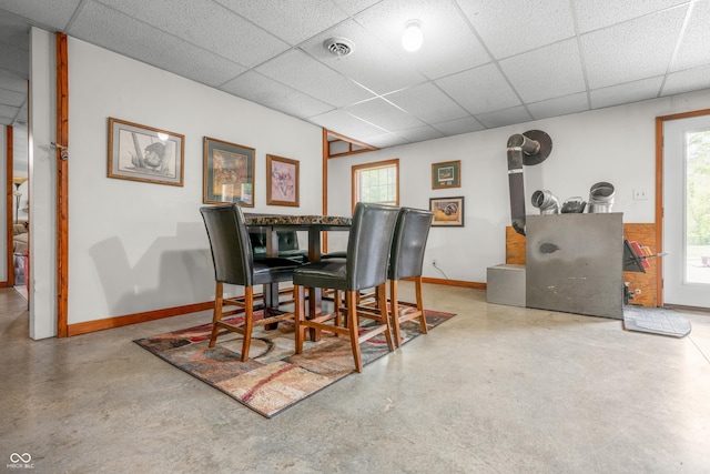 dining space with a drop ceiling, plenty of natural light, baseboards, and concrete flooring