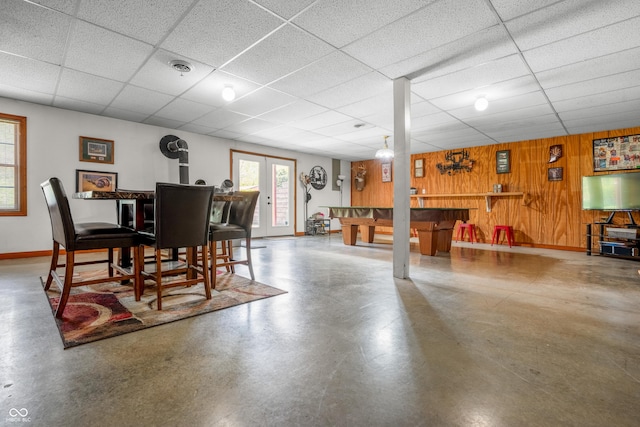 dining area with concrete floors, wood walls, a paneled ceiling, baseboards, and billiards