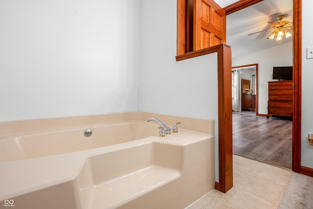full bathroom featuring a bath, ceiling fan, baseboards, and lofted ceiling