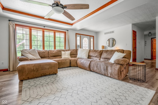 living room with wood finished floors, a textured ceiling, a ceiling fan, baseboards, and a raised ceiling