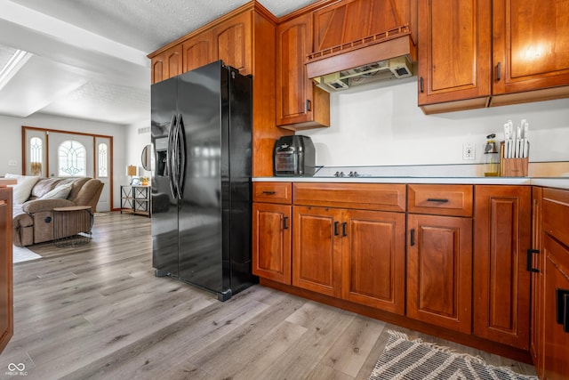 kitchen featuring black fridge, light wood-style flooring, exhaust hood, open floor plan, and brown cabinetry