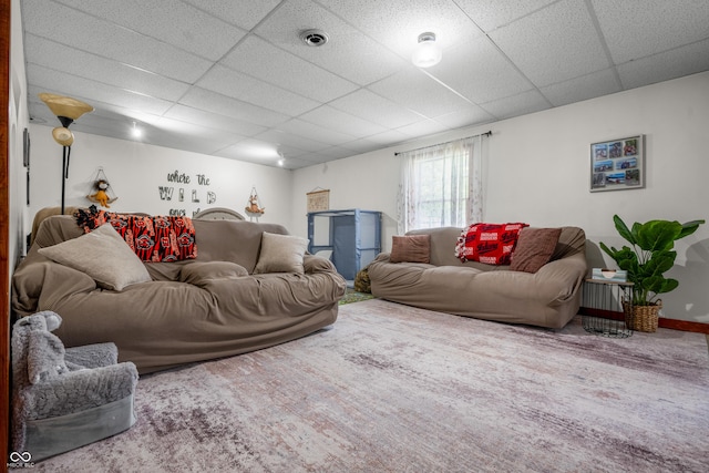 living room featuring a drop ceiling and baseboards