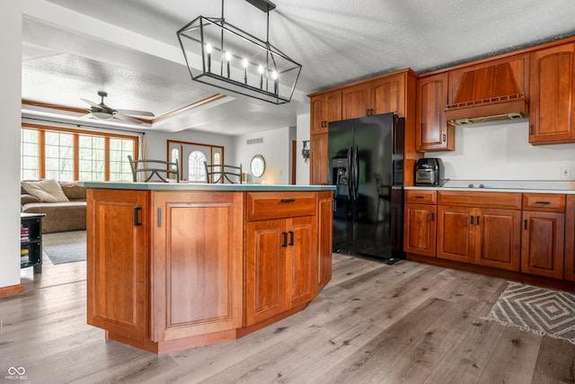 kitchen featuring black fridge with ice dispenser, premium range hood, light wood-style floors, brown cabinets, and a ceiling fan