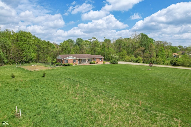 view of front of property featuring a front yard, a forest view, and brick siding