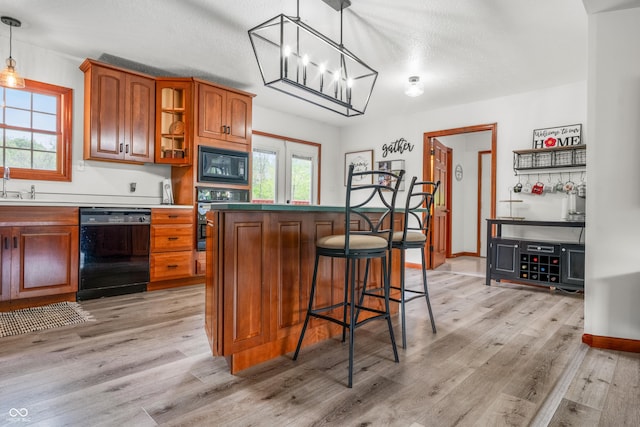 kitchen featuring black appliances, brown cabinetry, light wood-style flooring, a kitchen island, and glass insert cabinets