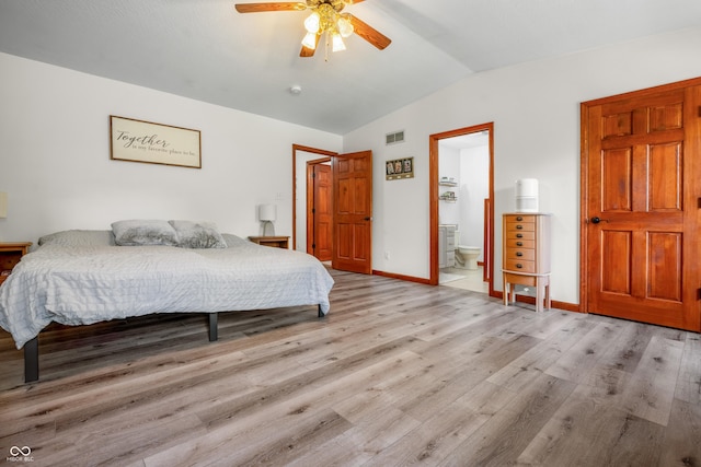 bedroom featuring vaulted ceiling, wood finished floors, baseboards, ensuite bathroom, and ceiling fan