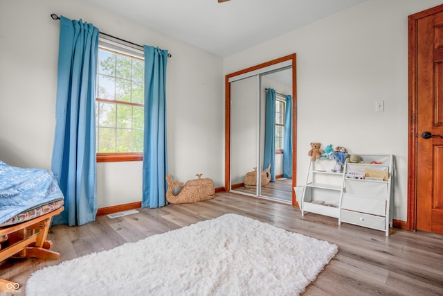 bedroom with wood finished floors, a closet, and baseboards