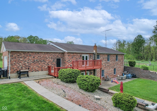 back of house featuring a wooden deck, a patio area, brick siding, and roof with shingles