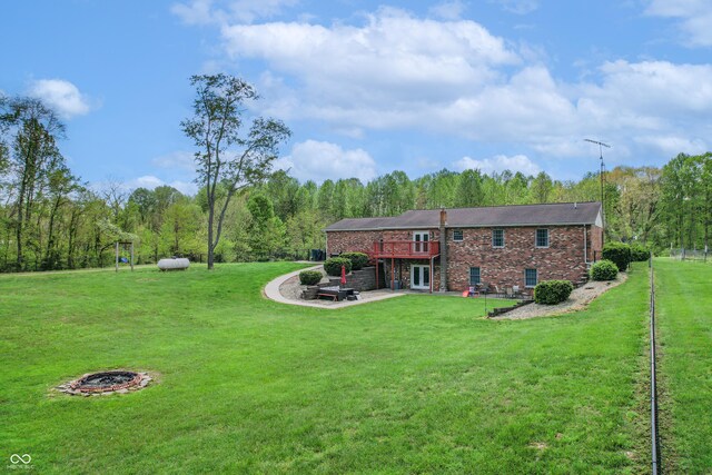 rear view of property featuring a lawn, a wooden deck, and brick siding