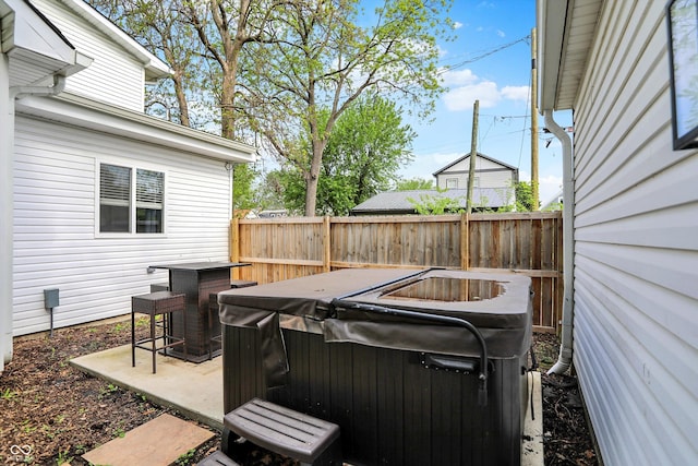 wooden deck with a hot tub, fence, and a patio area