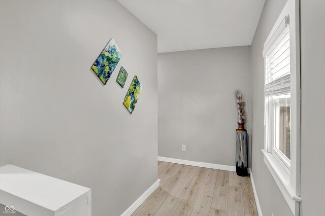 corridor featuring light wood-style flooring and baseboards