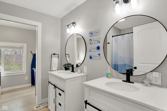 bathroom featuring wood finished floors, two vanities, and baseboards