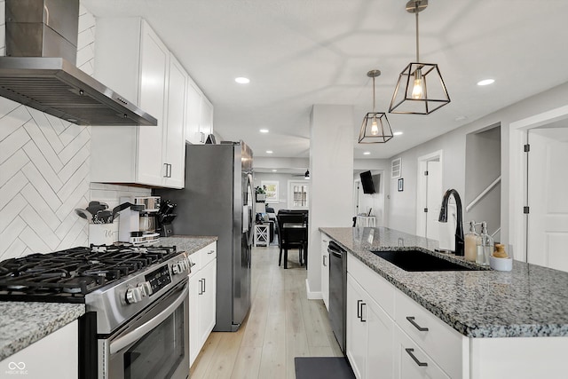 kitchen featuring stainless steel gas range, wall chimney range hood, a sink, black dishwasher, and a kitchen island with sink