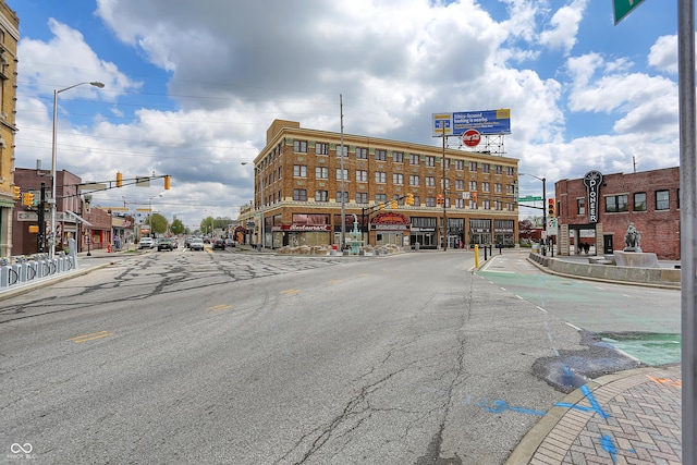 view of asphalt road featuring street lights, sidewalks, and traffic lights