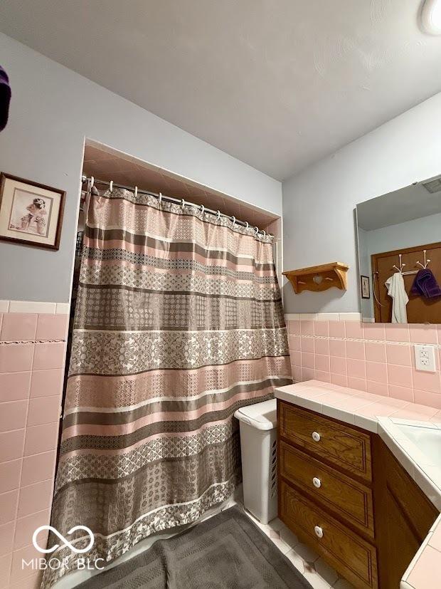 bathroom featuring tile walls, vanity, wainscoting, and a shower with shower curtain