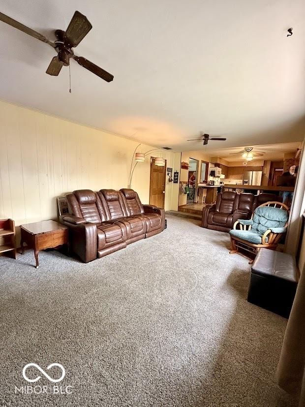 living area featuring a ceiling fan and carpet