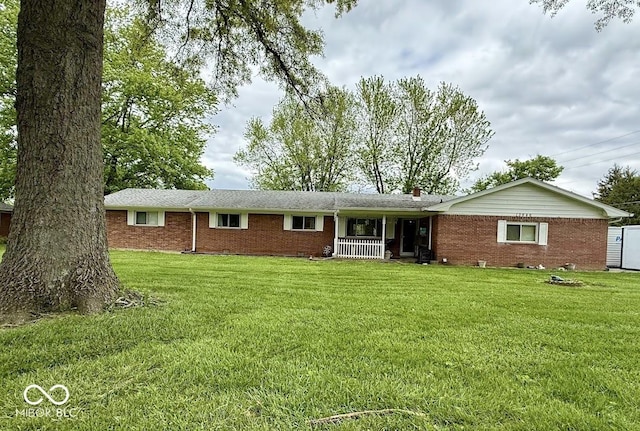 ranch-style home featuring brick siding, a front yard, and covered porch