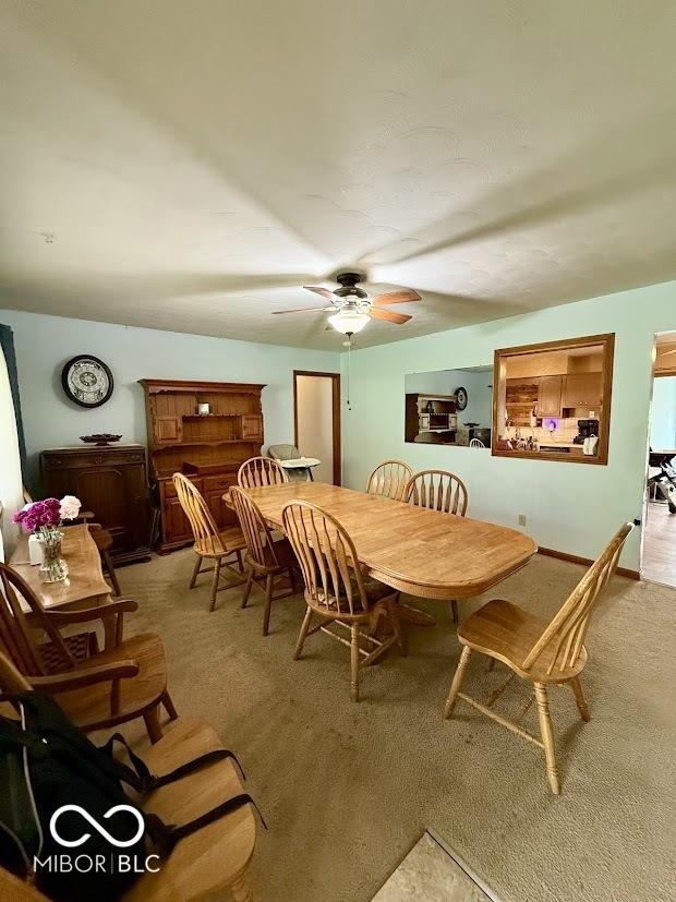 dining space featuring light carpet and a ceiling fan