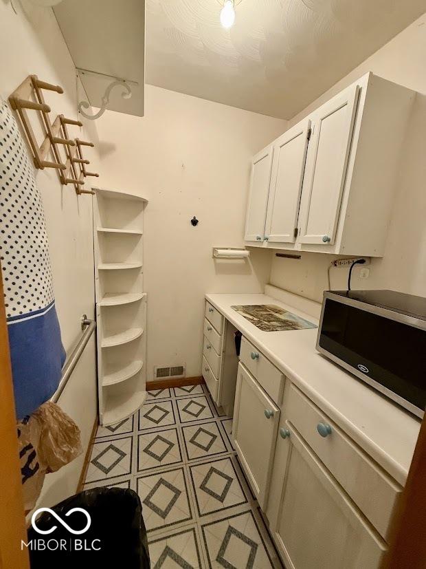 clothes washing area with light tile patterned flooring and baseboards