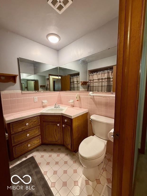 full bath featuring toilet, vanity, decorative backsplash, and tile patterned floors